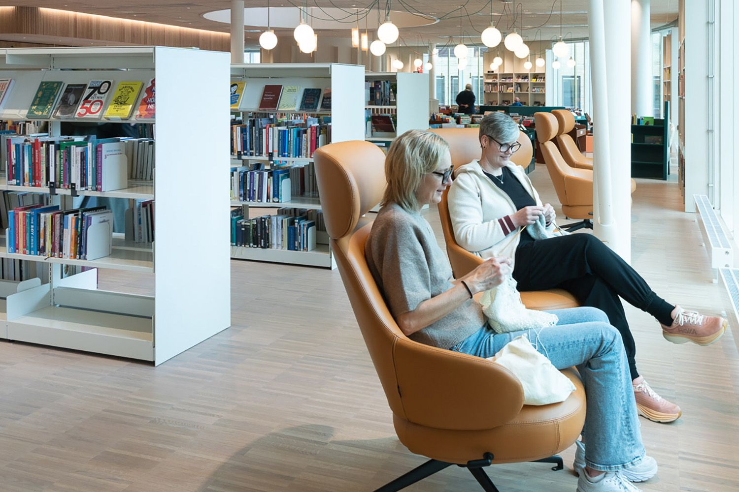 2 damer sitter og strikker i et bibliotek