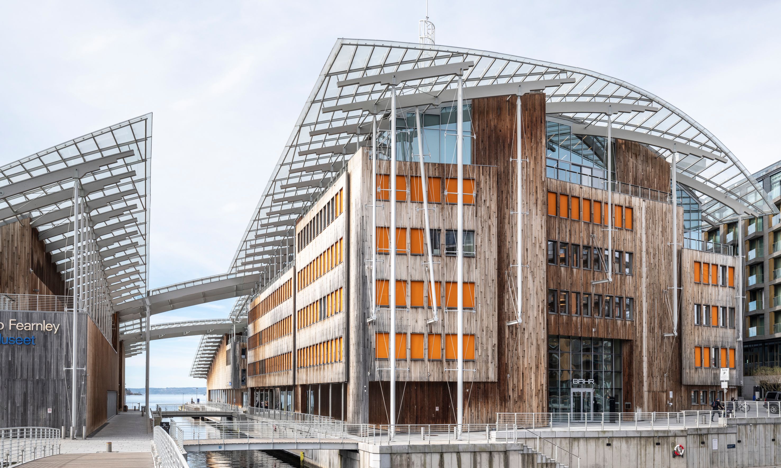 The Astrup Fearnley Museum: modern wood and glass buildings with distinctive roofs by a canal.