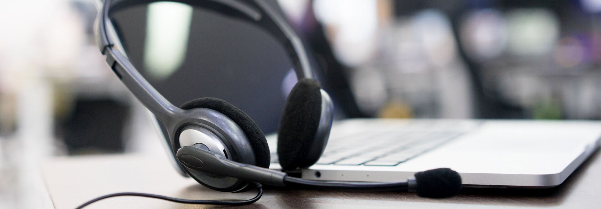 et par hodetelefoner med en mikrofon ligger på et tastatur.