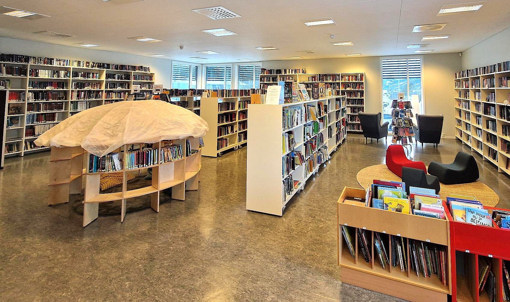 A brightly lit modern library with numerous bookshelves, comfortable seating areas, and a unique mushroom-shaped display.