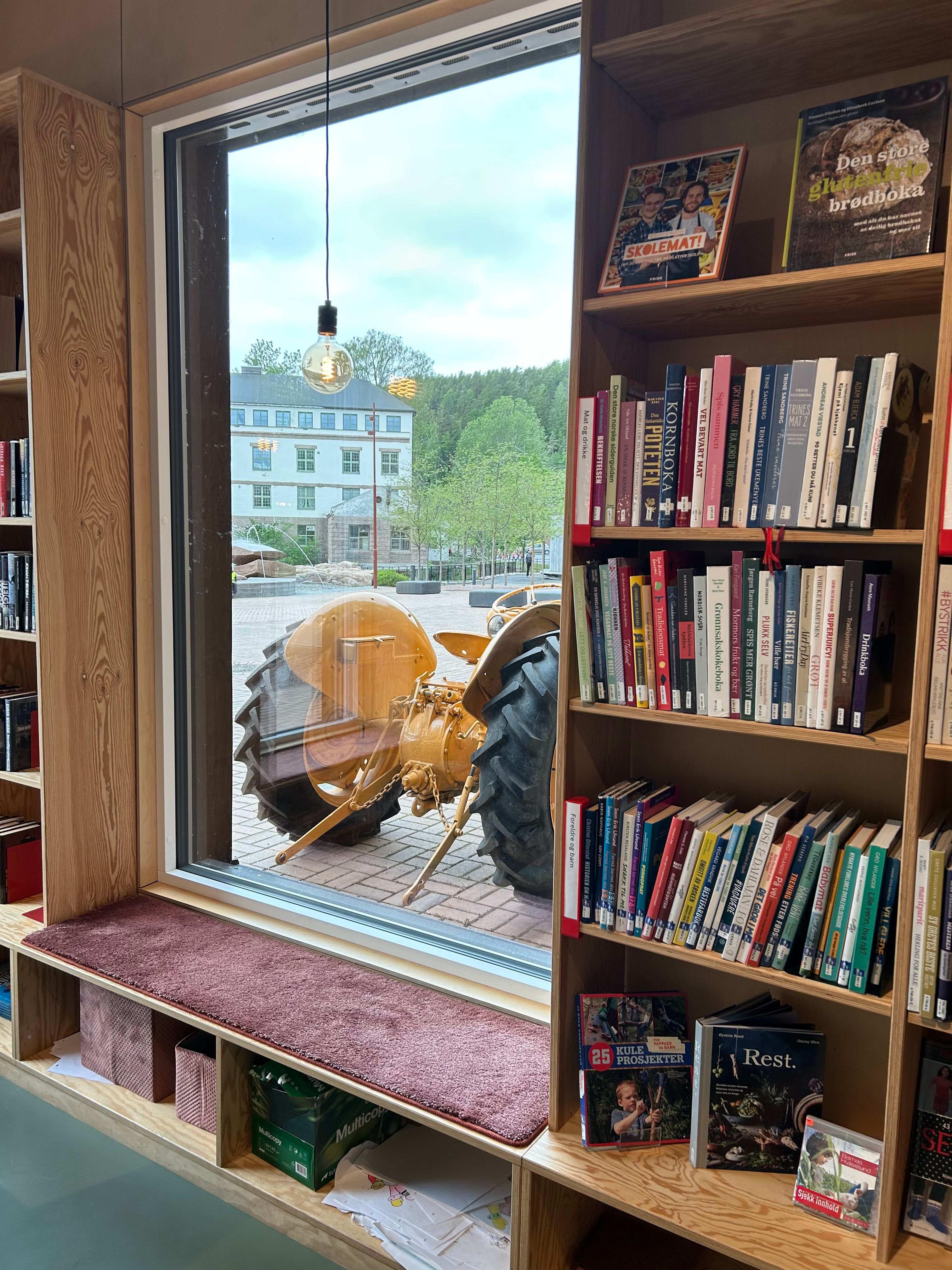 et bibliotek med en høyt vindu med en gul traktor utenfor