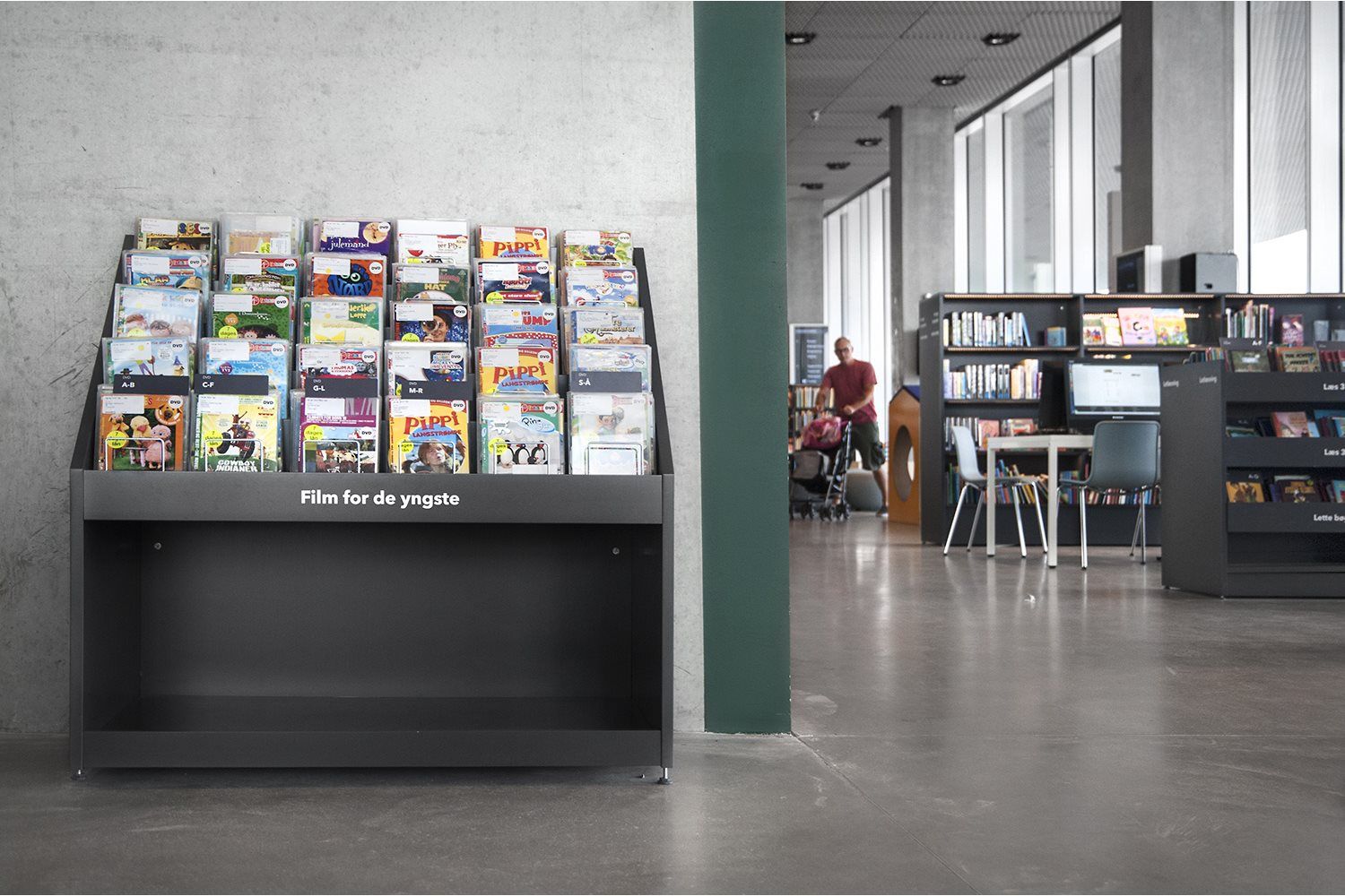 en bokkrybbe for dvd og cd står inntil veggen på et bibliotek