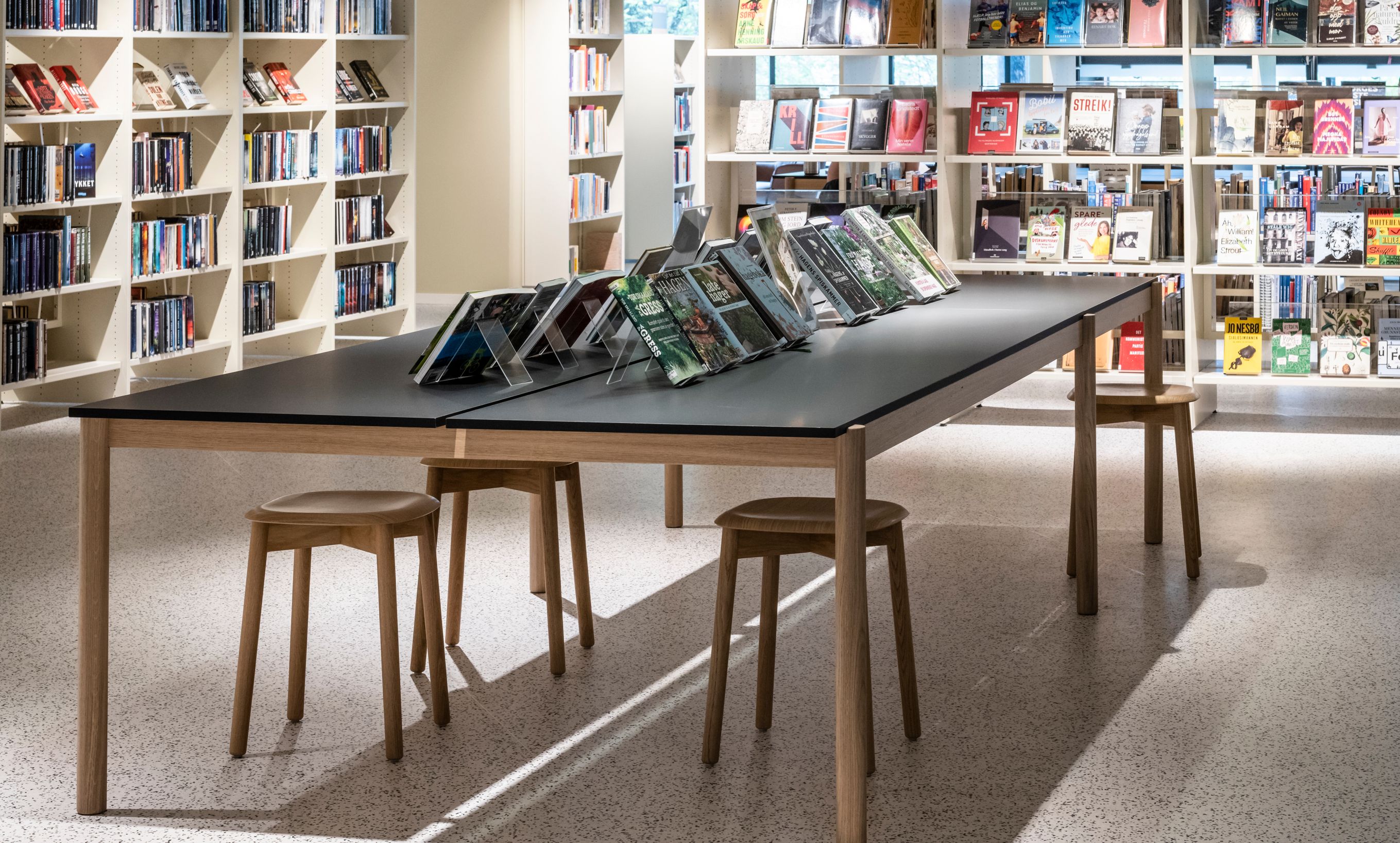 det er et bord og krakker i midten av biblioteket.