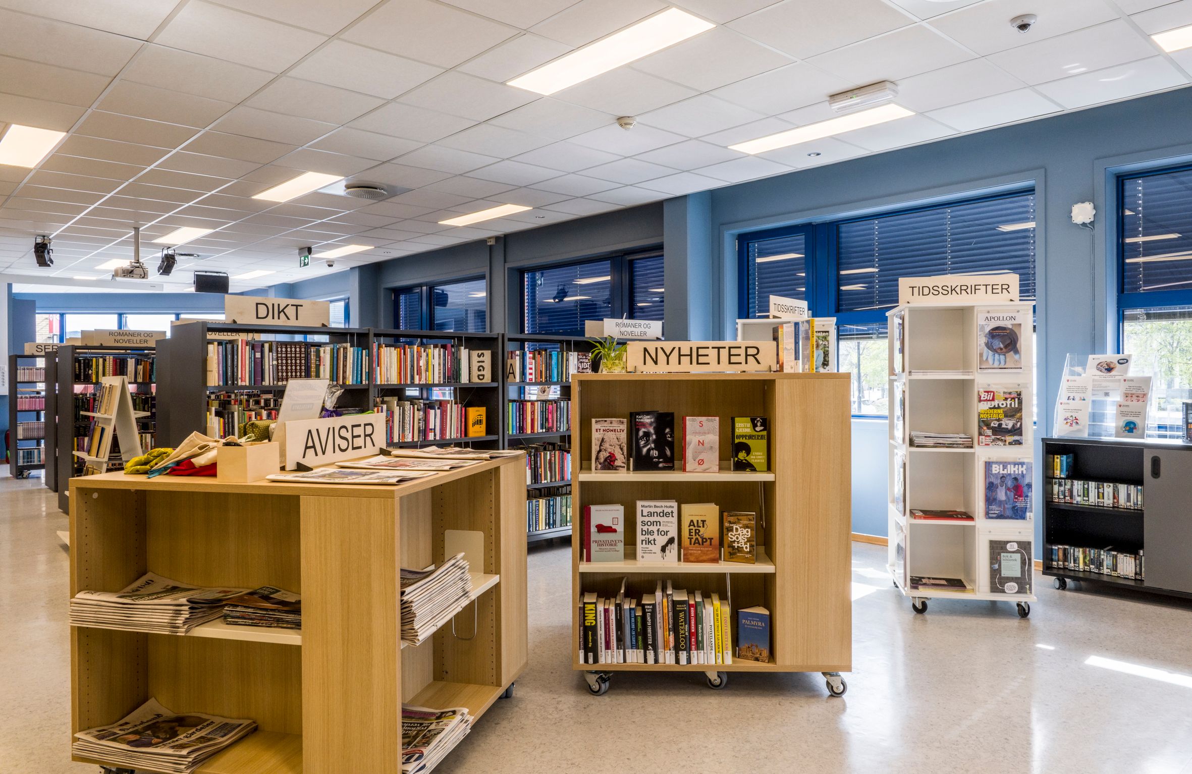 et bibliotek med lave utstillingsreoler i eik og et hvitt utstillingstårn for tidsskrifter