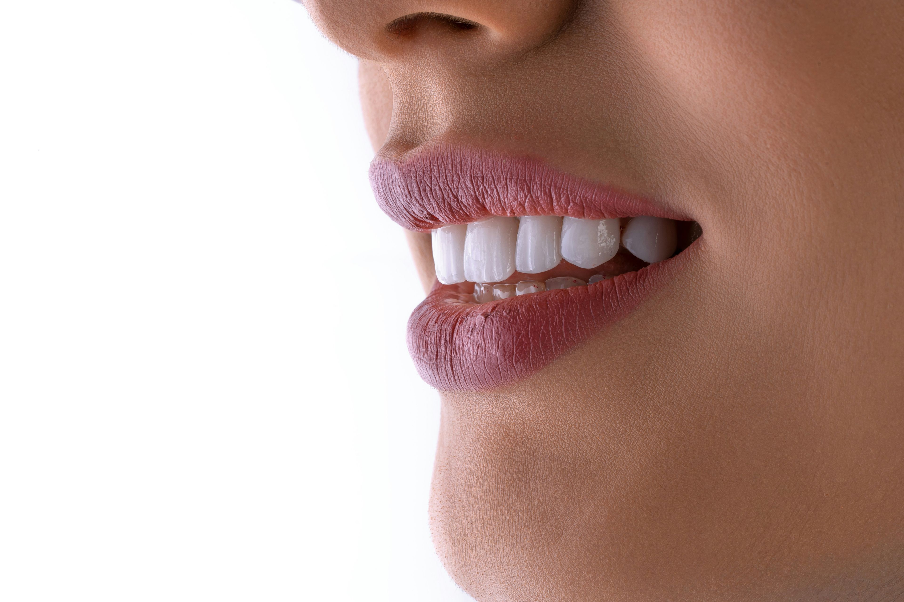 a close up of a woman 's mouth with white teeth and pink lips .