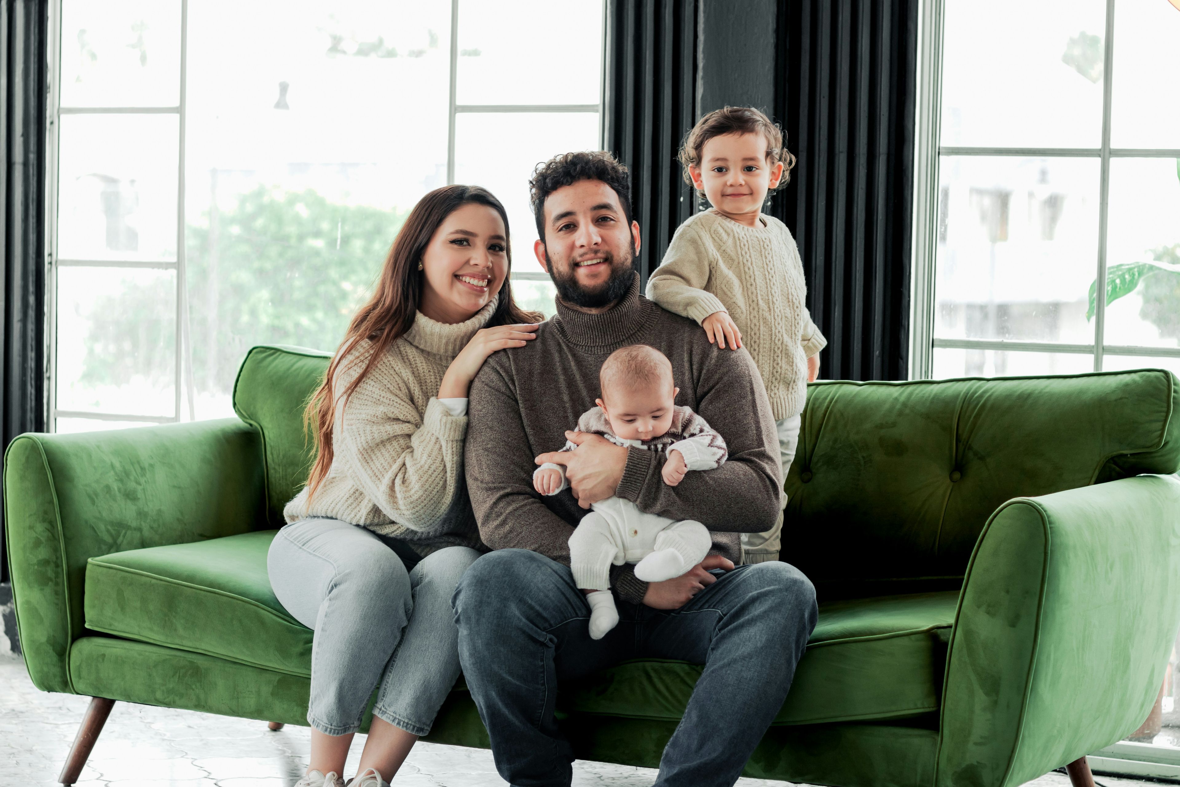a family is posing for a picture while sitting on a green couch .