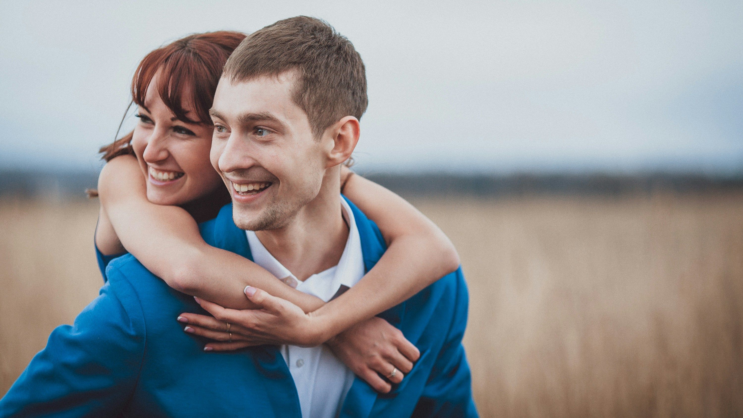 a man is carrying a woman on his back in a field .