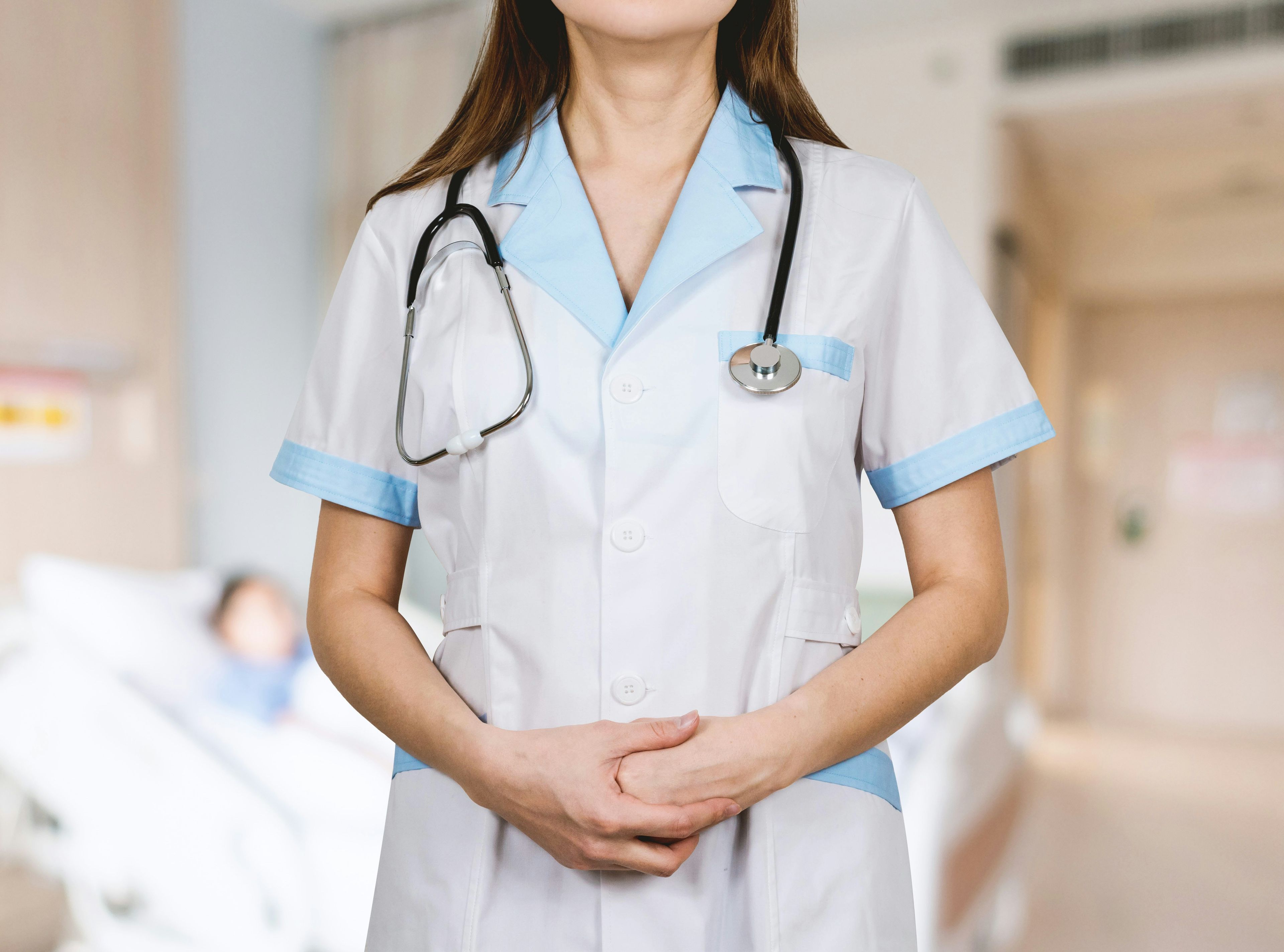 a nurse with a stethoscope around her neck is standing in a hospital room .