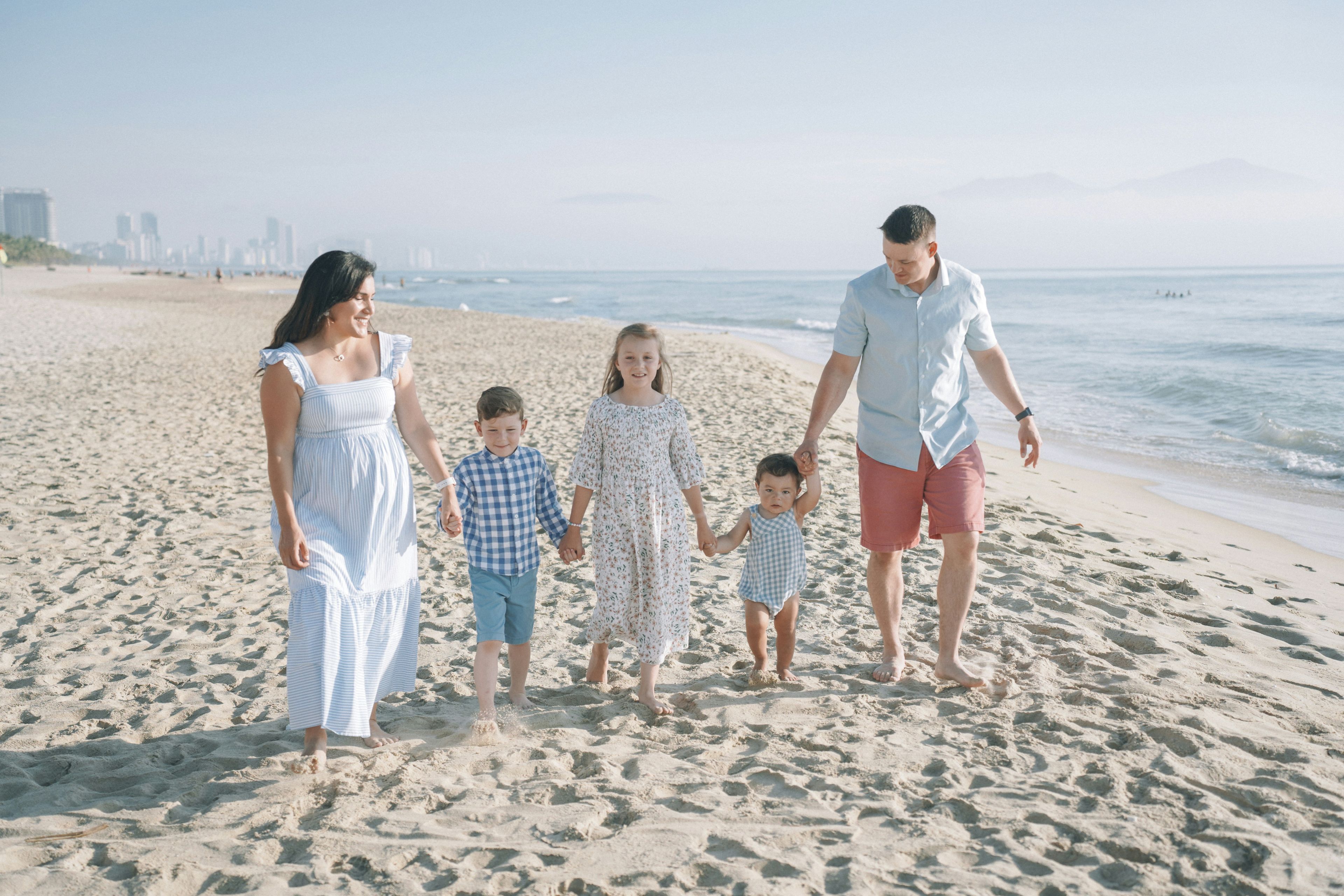 a family is walking on the beach holding hands .