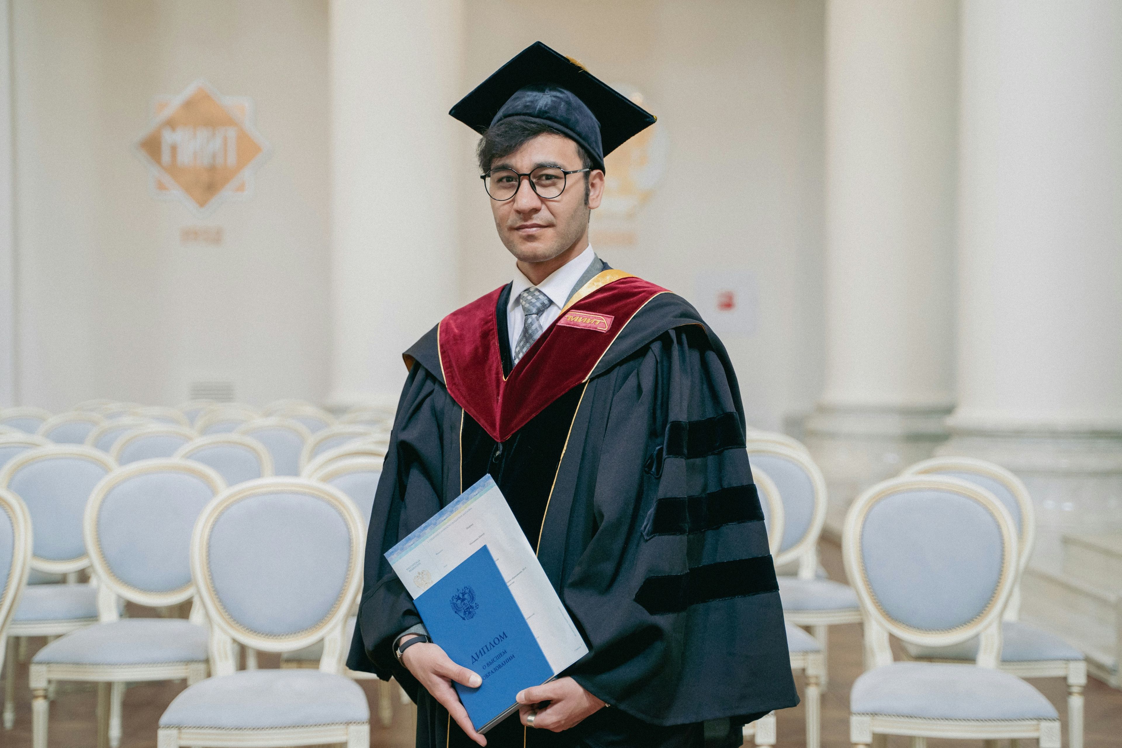 a man in a graduation cap and gown is holding a diploma .