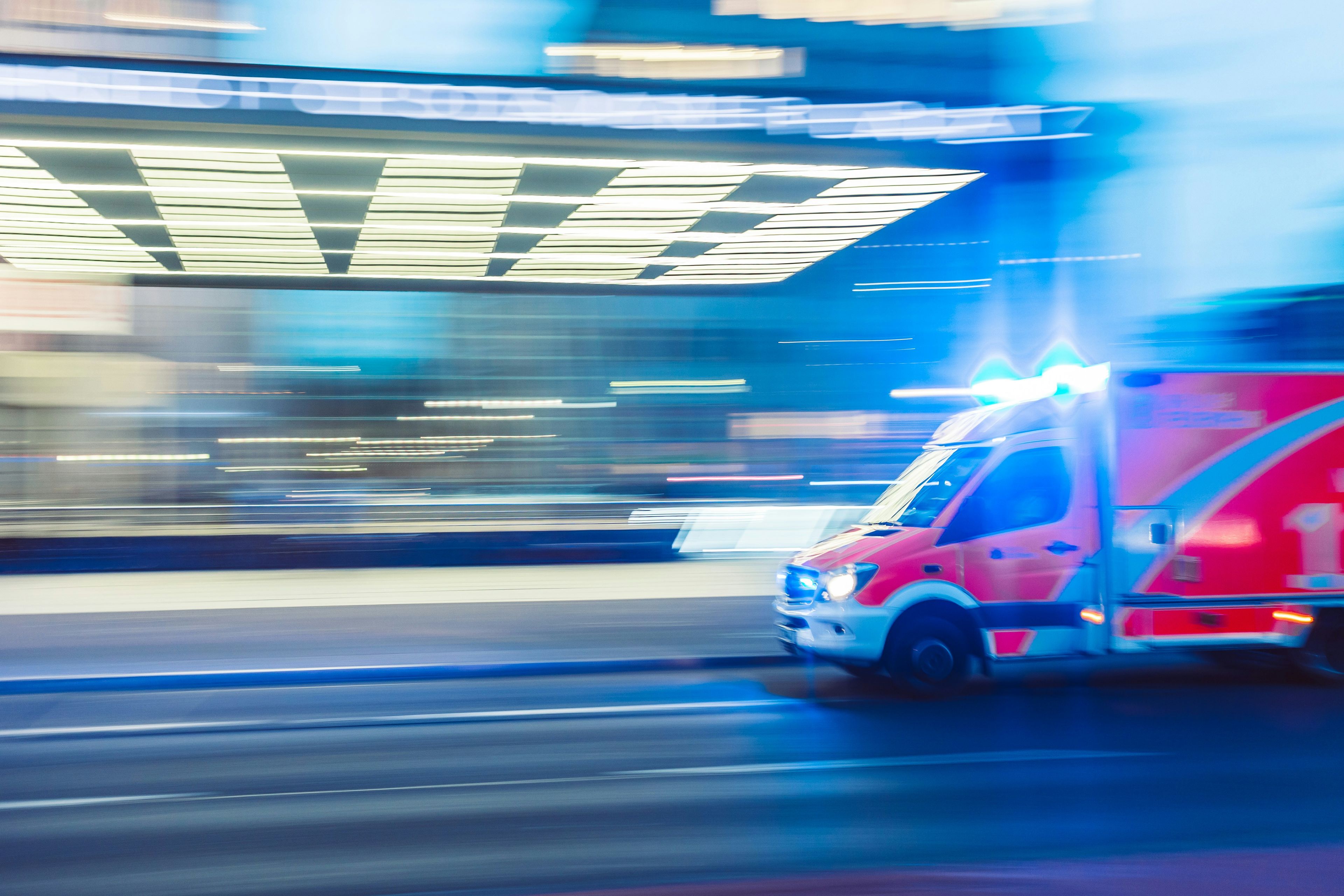 an ambulance is driving down a city street at night .
