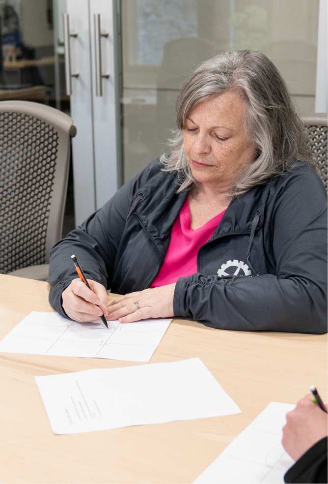 A participant drawing on paper at a table during the standard work exercise