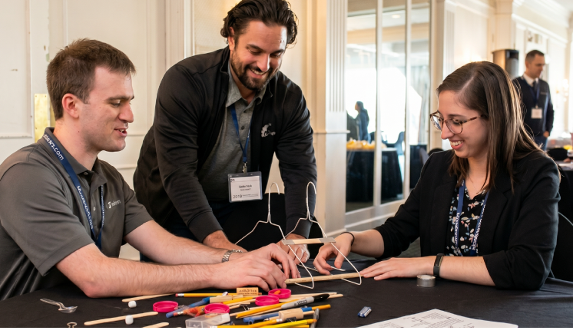 A team testing their assembled catapult alongside craft supplies on a workshop table