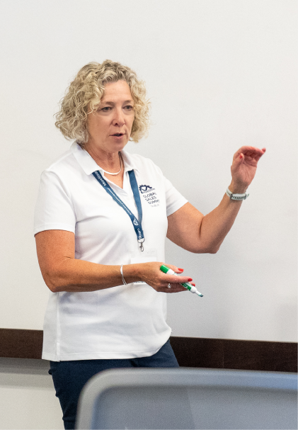A MoreSteam facilitator explaining the paper airplane exercise to a class