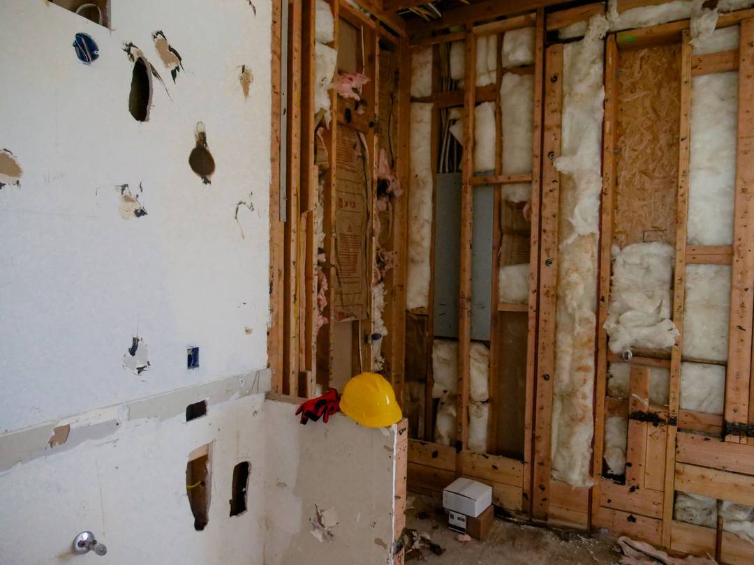 Rum under renovering med blotlagte vægge og gulv, hvor materialerne bør testes for asbest først