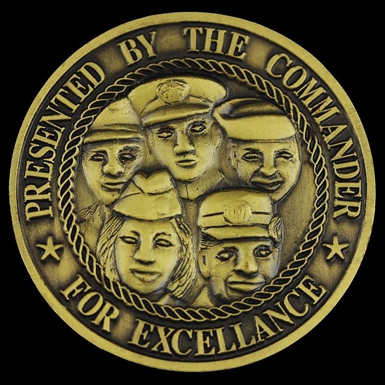 Antique bronze coin with five sculpted faces in service caps in high relief, ringed by raised lettering and a rope border.