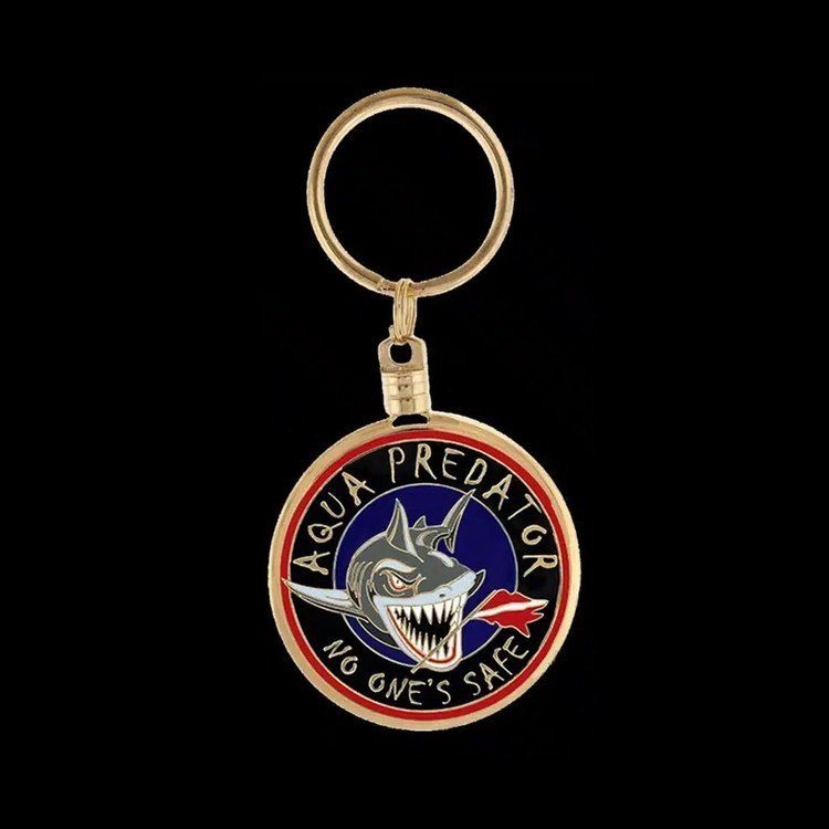 Round gold-tone enamel key chain with a shark design and the words Aqua Predator, No One's Safe, on a split key ring.
