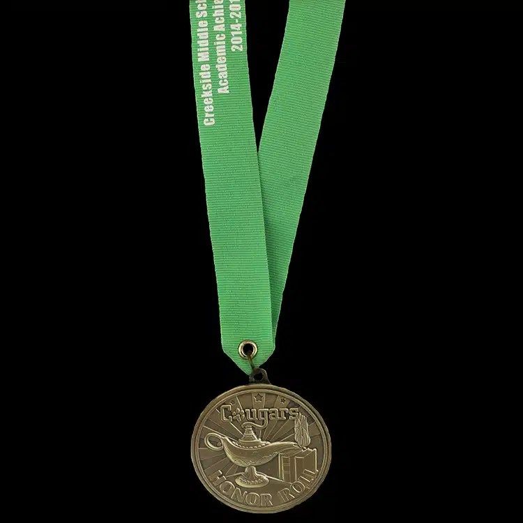 Antique bronze medal with a raised lamp of learning, hanging from a green neck ribbon printed with white lettering.
