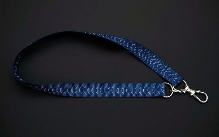 Navy flat polyester lanyard with a fine ribbed weave and a white screen printed wave pattern, finished with a silver J-hook.