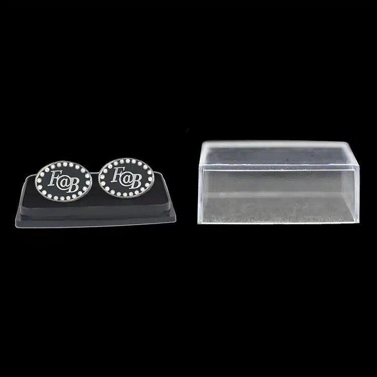 Round monogram cuff links displayed on a stand with a clear case.