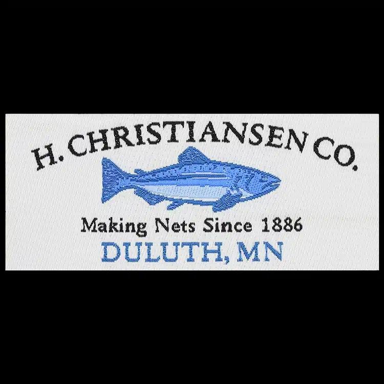 White straight-cut woven label with a blue fish between arched black lettering and blue lettering below.