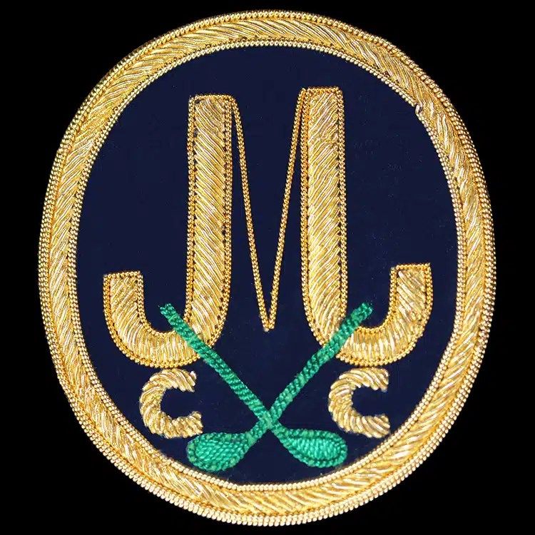 Hand embroidered gold bullion golf club crest with crossed clubs on navy.
