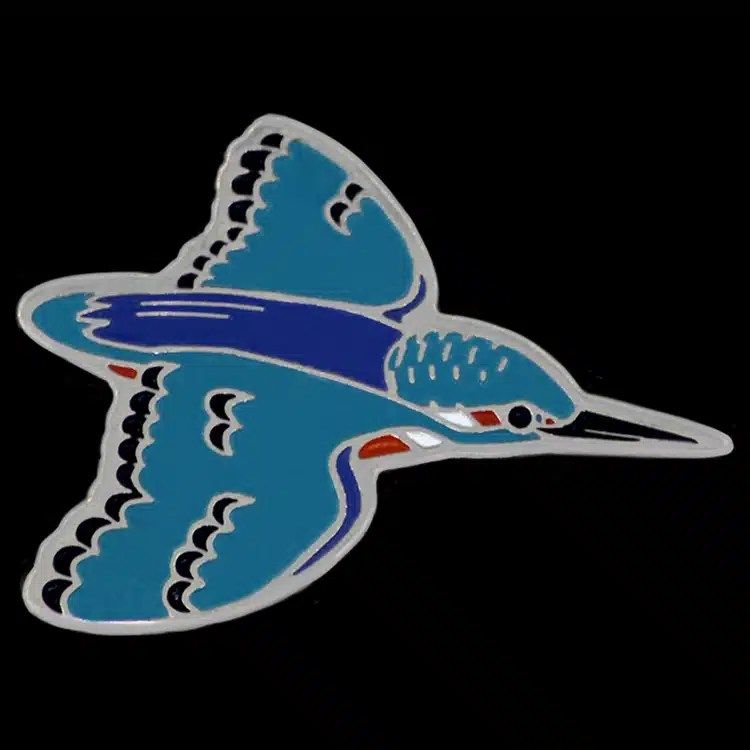 Photo etched lapel pin of a blue kingfisher in flight with fine line colour fill and a polished silver outline.