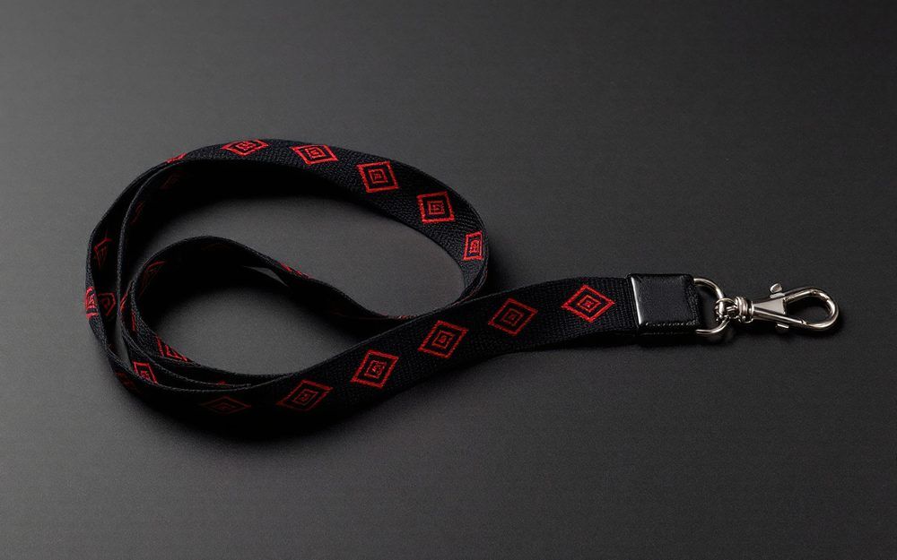 Black jacquard woven lanyard with red diamond motifs woven into the strap, finished with a silver lobster claw clip.