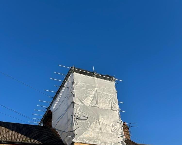 Sheeted scaffold tower around a chimney stack on a terraced house