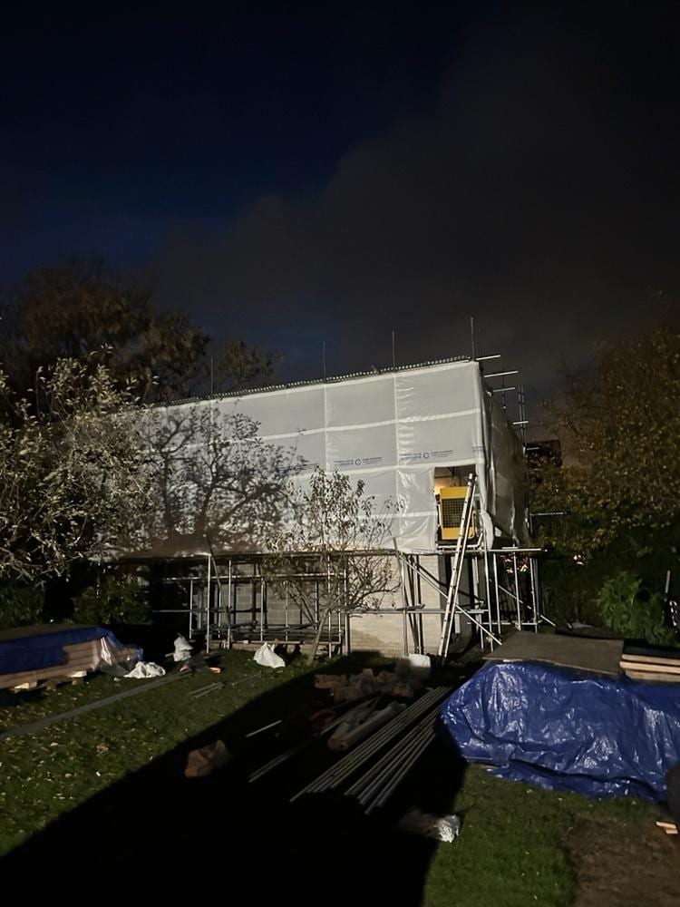 Fully sheeted scaffold encapsulating an extension at dusk