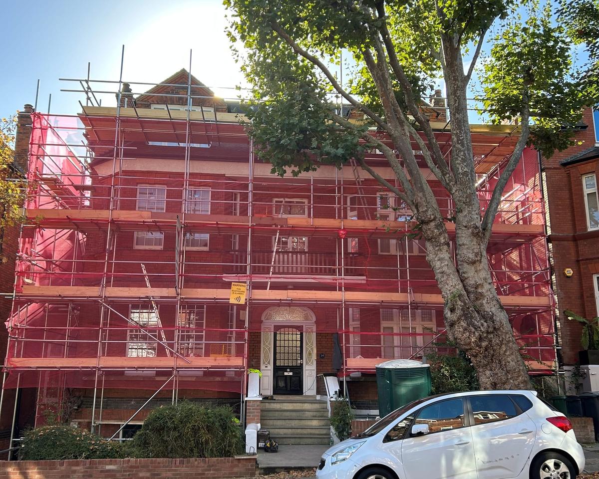 Scaffolding with red debris netting around a period block of flats