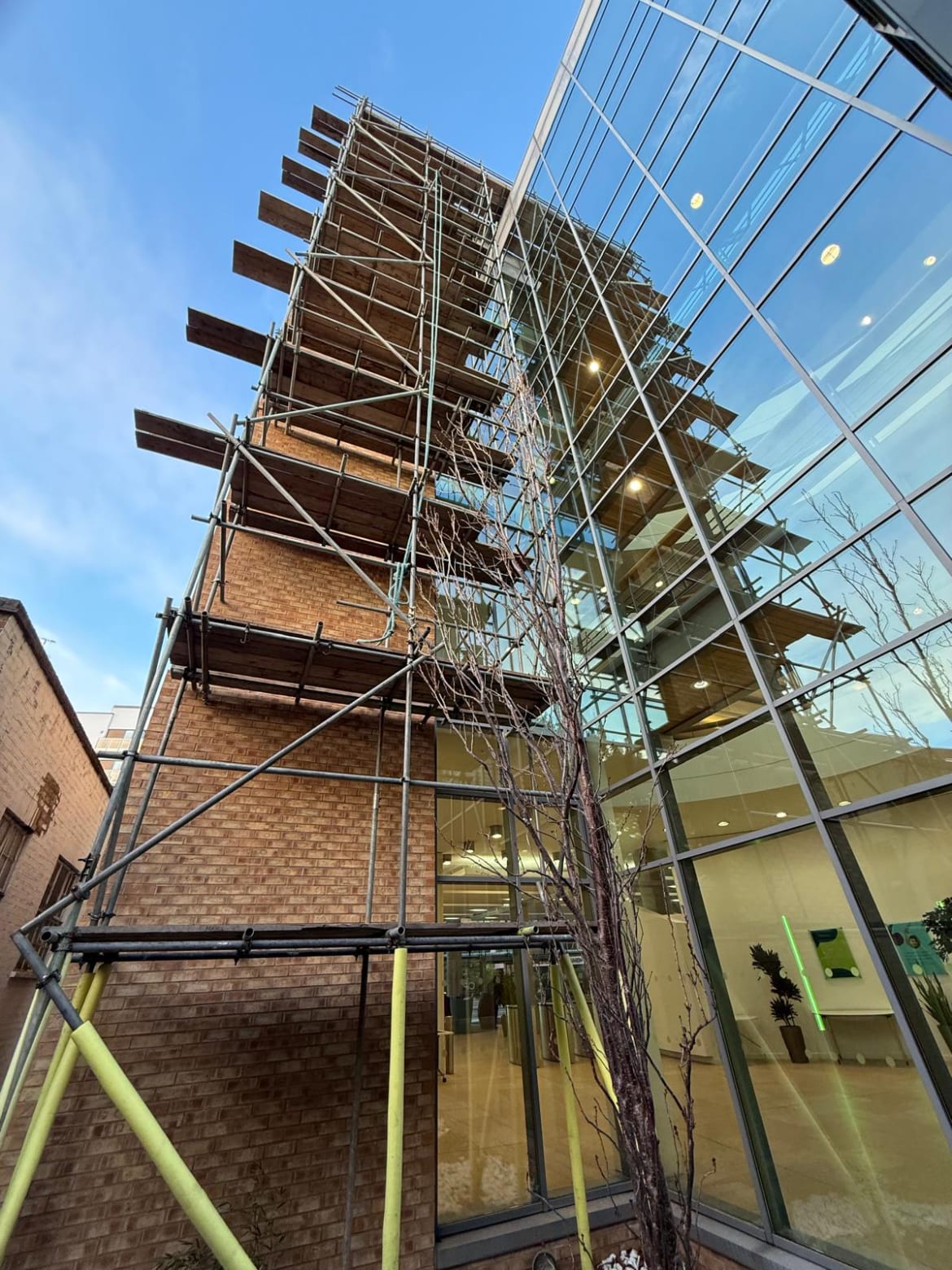 Scaffolding up the side of a brick and glass building