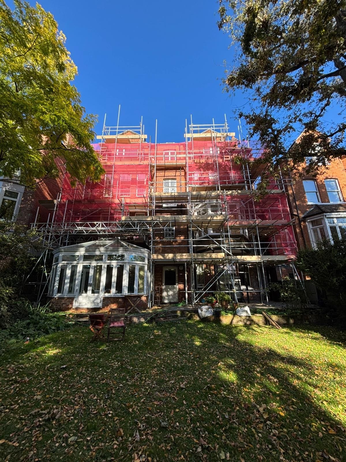 Scaffolding on a large three-storey house under a blue sky