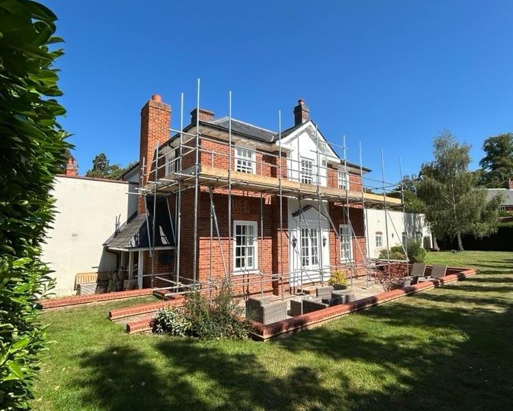 Scaffolding around a red-brick family home with a white gable