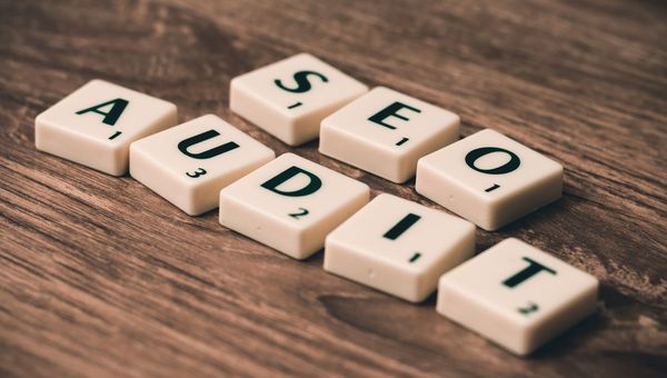 Buchstabensteine, die SEO AUDIT bilden, auf einem Holztisch