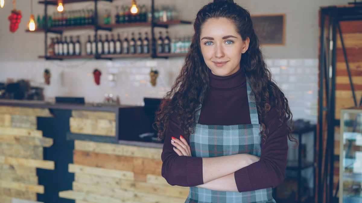 Gastronomin mit Schürze vor ihrem Tresen in einem lokalen Betrieb