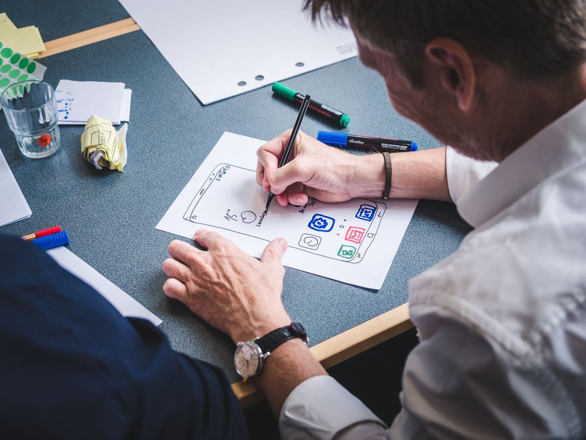 Designer sketching a page structure with a marker on a sheet of paper