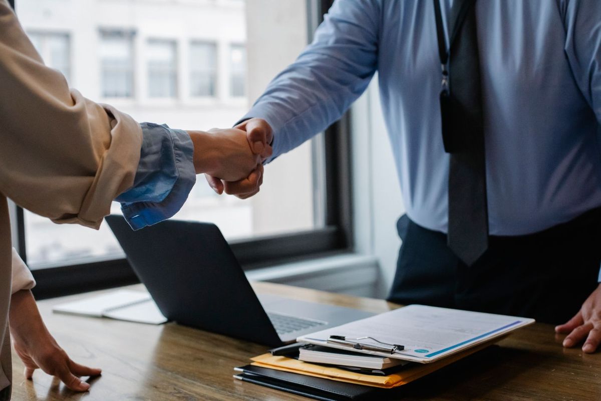 Handshake across a desk closing a service agreement