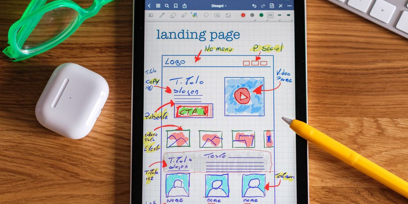 Hand-drawn landing page wireframe on a tablet lying on a wooden desk