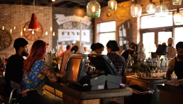 Salle de restaurant remplie de clients le soir, comptoir et tables occupées