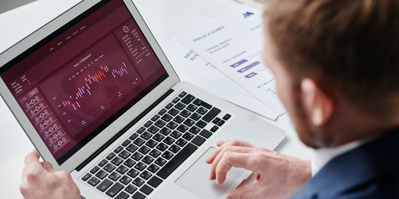 Geschäftsführer prüft ein Analyse-Dashboard auf dem Laptop, daneben gedruckte Berichte