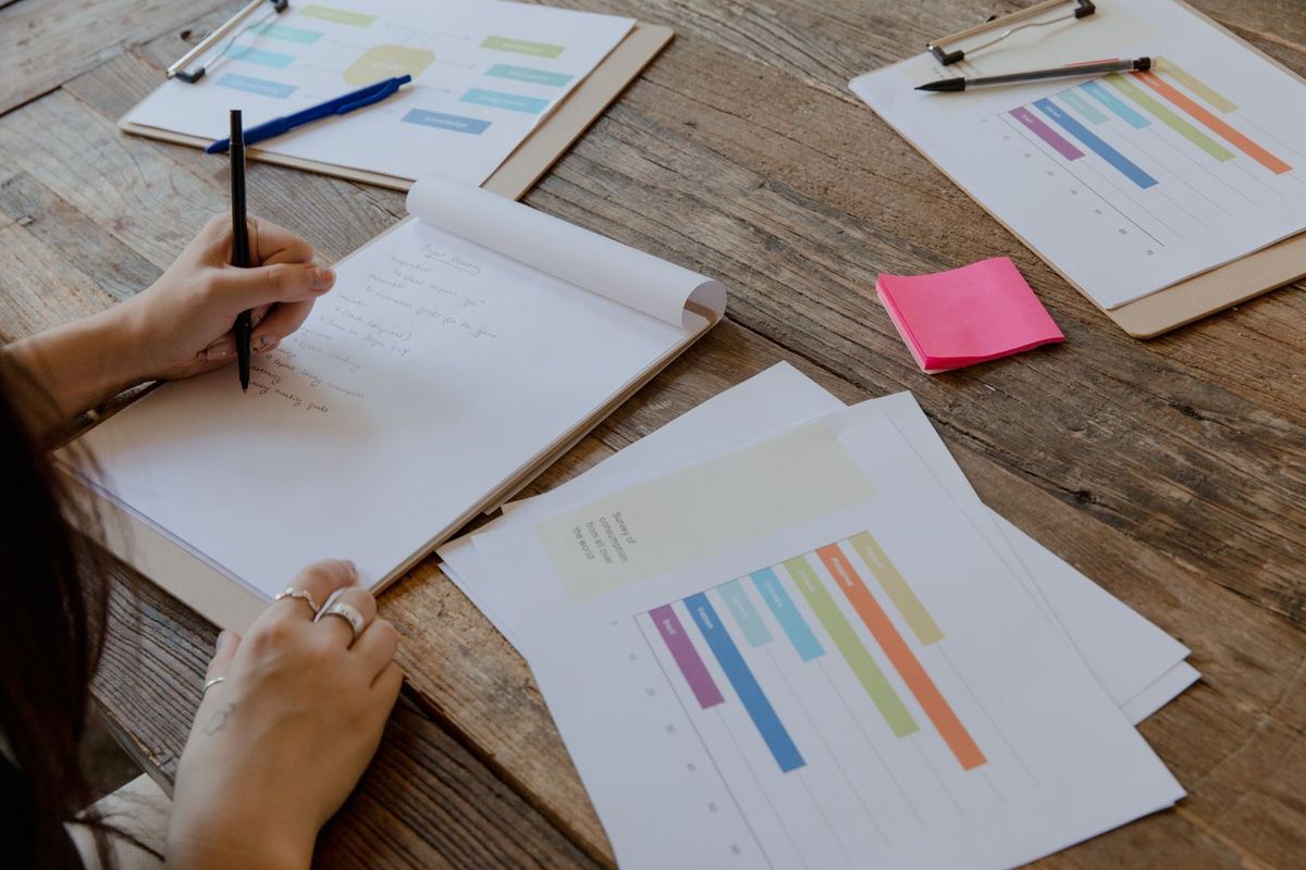 Person writing notes next to printed charts