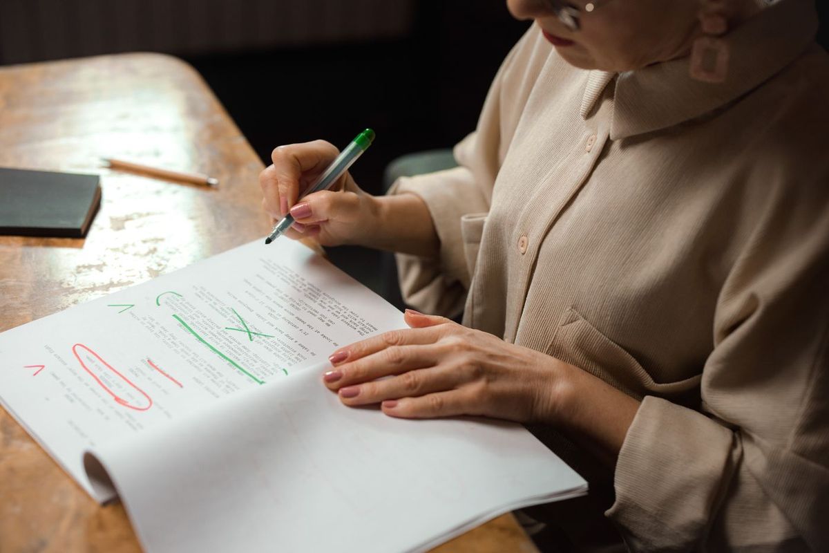 Woman rereading a printed text and marking corrections in green and red