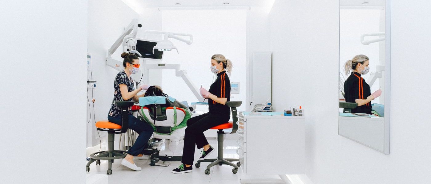 Modern dental practice with treatment chair and two practitioners during a consultation