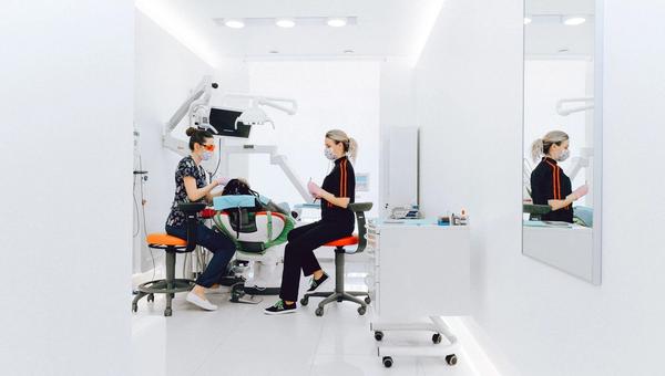 Modern dental practice with treatment chair and two practitioners during a consultation