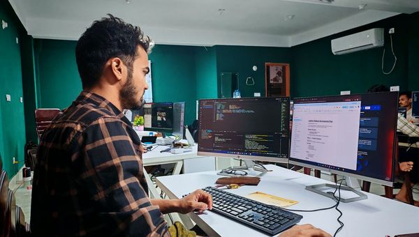 Développeur devant deux écrans de code, en train de reconstruire un site