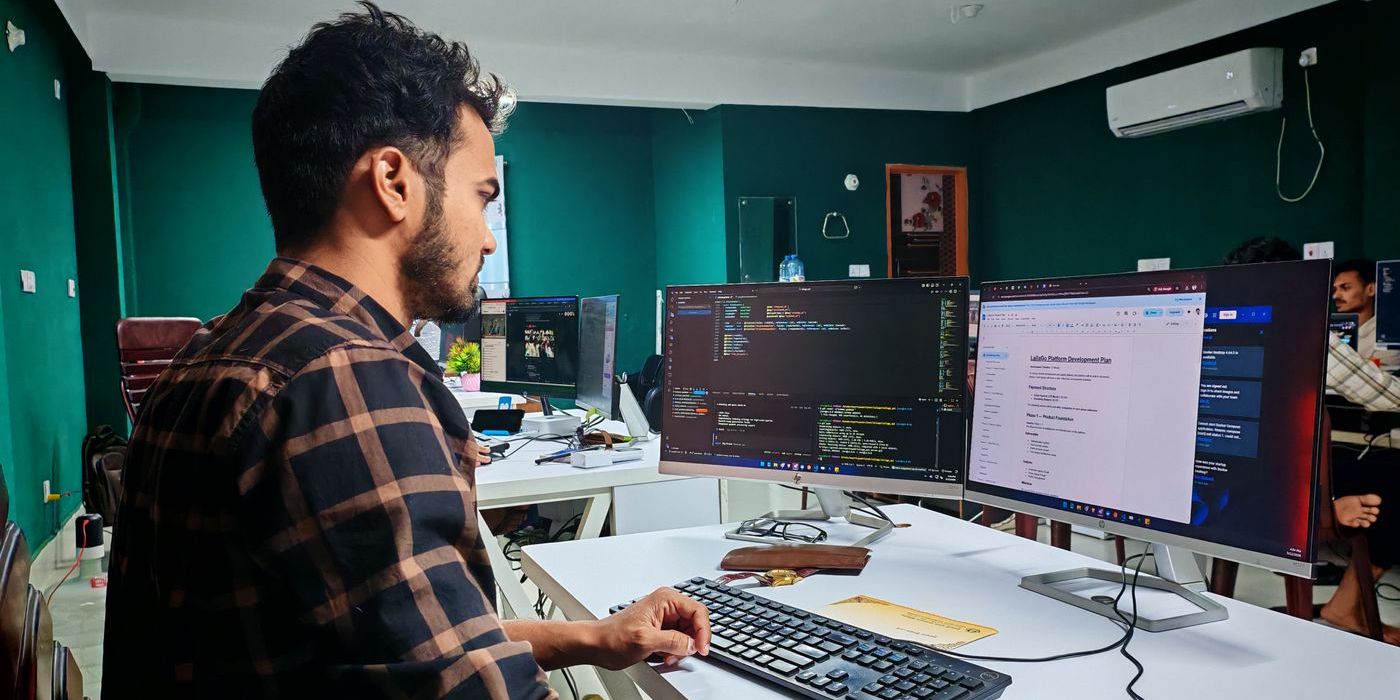 Developer at a desk rebuilding a website on two screens of code