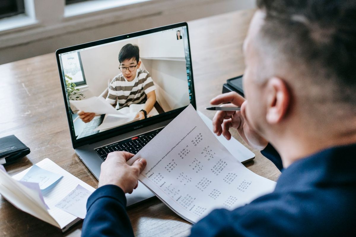 Video call debrief: two people going through a printed document, one on each side of the screen