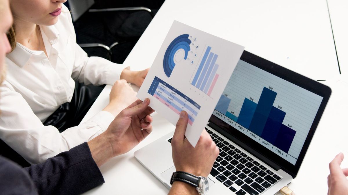 Two people comparing charts on a laptop during a meeting