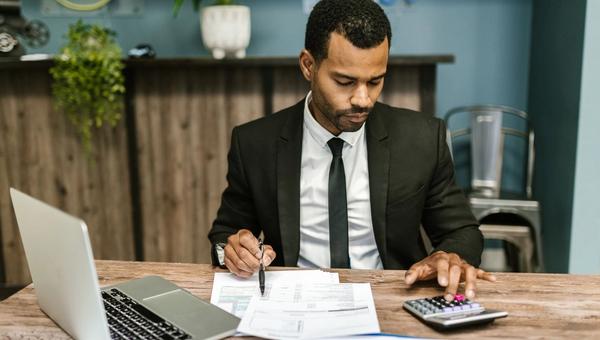 Business owner at a desk comparing quotes with a laptop and a calculator